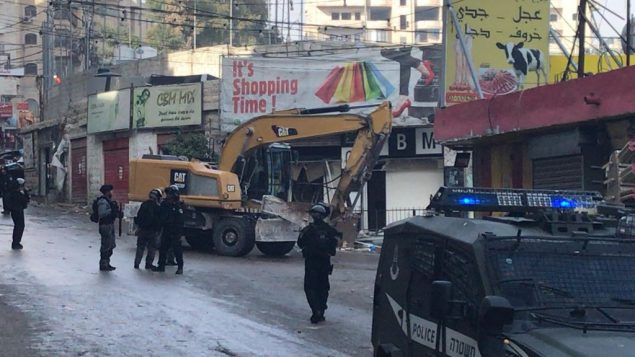 قوات الشرطة ترافق جرافات تهدم متاجر في مخيم شعفاط بالقدس الشرقية، 21 نوفمبر 2018 (Courtesy Ir Amim) قوات الشرطة ترافق جرافات تهدم متاجر في مخيم شعفاط بالقدس الشرقية، 21 نوفمبر 2018 (Courtesy Ir Amim)