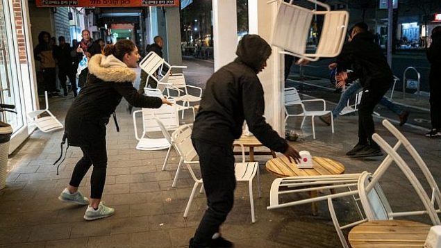 متظاهرون إثيوبيون إسرائيليون يقومون بتخريب مقهى على جانب الطريق في جادة ’ابن غابيرول’ في تل أبيب، 20 يناير، 2019. (Luke Tress/Times of Israel)