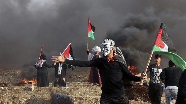 فلسطينيون يحملون اعلام بينما يتصاعد دخان اطارات مشتعلة خلال اشتباكات بالقرب من الحدود بني قطاع غزة واسرائيل، 9 نوفمبر 2018 (AP Photo/Adel Hana)