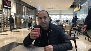 شهير فروع السوبر ماركت رامي ليفي يشرب القهوة في مجمع عتاروت، مجمعه الجديد على خط التماس بين القدس العربية واليهودية. (Jessica Steinberg/Times of Israel)