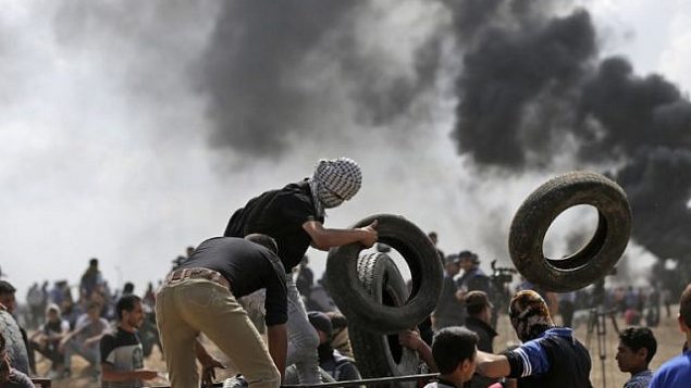 متظاهرون فلسطينيون يحرقون إطارات بالقرب من حدود غزة-إسرائيل، شرق مدينة غزة، خلال مظاهرات احتجاجا على افتتاح السفارة الأمريكية في القدس، 14 مايو، 2018.  (AFP Photo/Mahmud Hams)