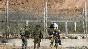 توضيحية: جنود إسرائيليون يحملون مصابا فلسطينيا يقول الجيش إنه حاول اختراق السياج الحدودي شرقي جباليا في شمال قطاع غزة، 27 يونيو، 2018. (Said Khatib/AFP)
