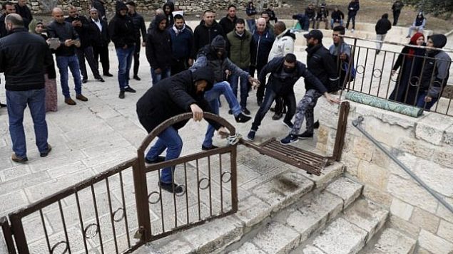 متظاهرون فلسطينيون يقومون بتحطيم وفتح بوابة مغلقة في المسجد الأقصى في القدس القديمة، 18 فبراير، 2019. (Ahmad Gharabli/AFP).