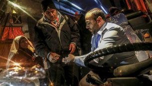 شرطي تابع لحركة حماس يفحص وثائق سفر معتمرين فلسطينيين يصعدون على متن حافلة في معبر رفح بين قطاع غزة ومصر، 3 مارس 2019 (SAID KHATIB / AFP)