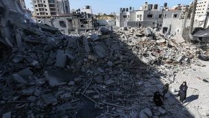 صورة تم التقاطها في 26 مارس، 2019، يظهر فيها فلسطينيون يقفون بالقرب من أنقاض أحد المباني في مدينة غزة، بعد أن استهدفت غارات جوية إسرائيلية عشرات المواقع في جميع أنحاء القطاع ليلا ردا على إطلاق صاروخ من القطاع الفلسطيني.  (MAHMUD HAMS / AFP)