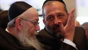 زعيم ’شاس’، عضو الكنيست أرييه درعي (من اليمين) يتحدث مع زعيم حزب ’يهدوت هتوراه’، عضو الكنيست يعقوب ليتسمان (من اليسار) خلال الجلسة الافتتاحية للكنيست ال20، 31 مارس، 2015.  (Nati Shohat/Flash90)