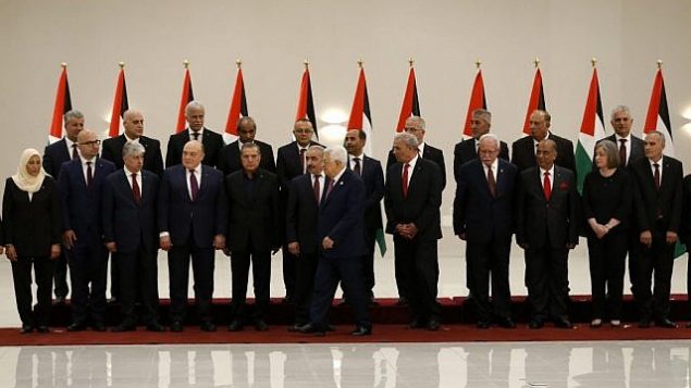 رئيس السلطة الفلسطينية محمود عباس (السادس من اليمين) يسير مبتعدا بعد التقاط صورة جماعية لأعضاء الحكومة الفلسطينية الجديدة في مدينة رام الله بالضفة الغربية، 13 أبريل، 2019. (Abbas Momani/AFP)
