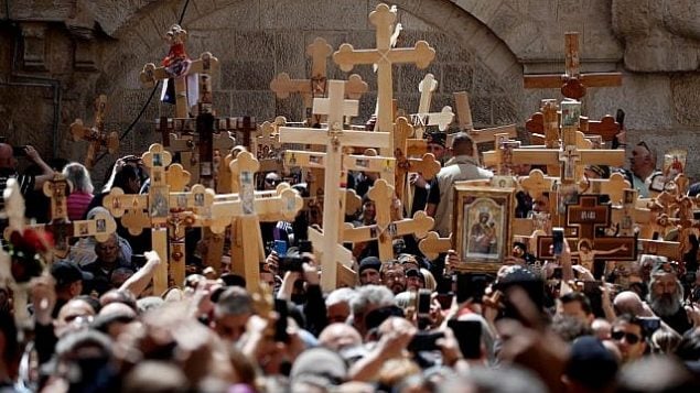 المسيحيون الأرثوذكس يدخلون بصلبان خشبية في كنيسة القيامة أثناء احتفالهم بيوم الجمعة العظيمة في موكب في طريق الآلام في البلدة القديمة في القدس، في 26 أبريل 2019. (Thomas Coex/AFP)