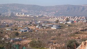صورة لقرية عرب النعيم البدوية في المقدمة، مع مدينة كرمئيل في الخلفية، 25 فبراير، 2006.  (Public Domain/Wikipedia)