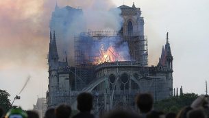 اشخاص يشاهدون الدخان والنيران تتصاعد من كاتدرائية نوتردام في باريس، 15 ابريل 2019 (AP Photo/Thibault Camus)