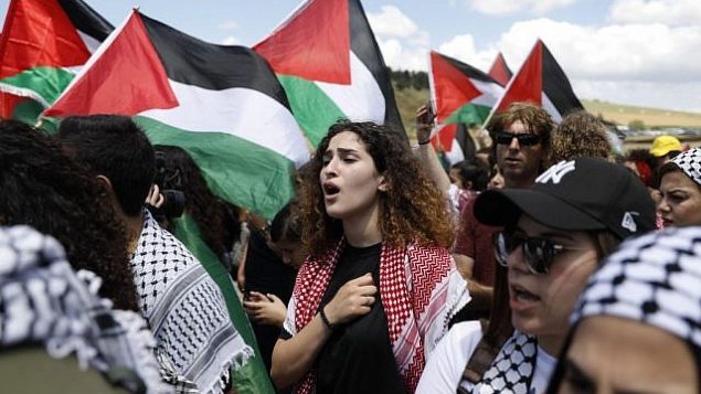 عرب من مواطني إسرائيل يرفعون الأعلام الفلسطينية خلال مشاركتهم في ’مسيرة العودة’ السنوية التي تجرى بالتزامن مع احتفال إسرائيل باستقلالها، بالقرب من مدينة أم الفحم في شمال البلاد، 9 مايو، 2019. (Ahmad Gharabli/AFP)
