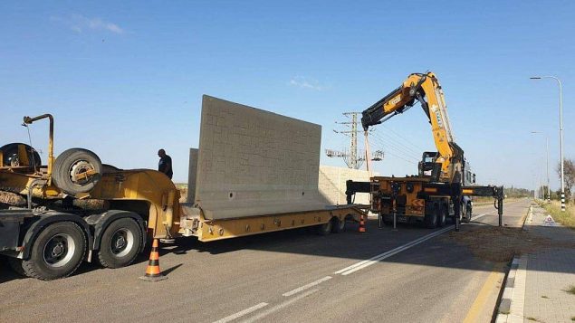 عمال ينصبون جدار على جانب طريق بالقرب من كيبوتس ايريز في جنوب اسرائيل لحمايته من الصواريخ، 8 مايو 2019 (Courtesy)
