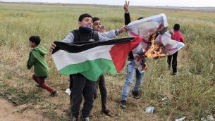 اطفال فلسطينيون يلوحون بالعلم الفلسطيني بينما يحرقون صورة الرئيس الامريكي دونالد ترامب، خلال مظاهرة ضخمة بالقرب من مدينة خان يونس في جنوب قطاع غزة، 30 مارس 2018 (Said Khatib/AFP)