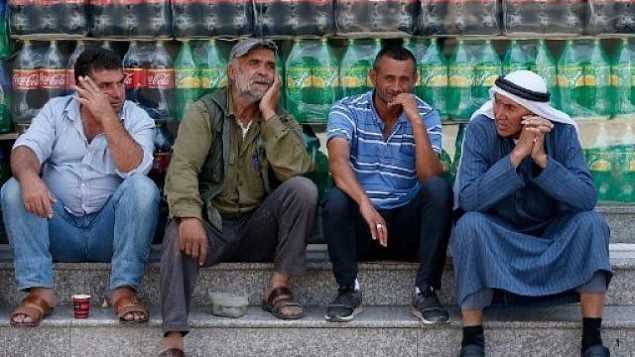 رجال فلسطينيون يتحادثون خلال تظاهرة ضد القمة الاقتصادية المنعقدة في البحرين برعاية أمريكية في مدينة يطا بالقرب من مدينة الخليل بالضفة الغربية، 24 يونيو، 2019. (HAZEM BADER / AFP)
