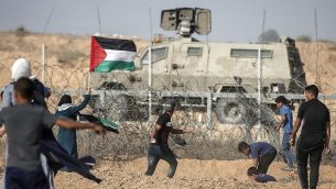 متظاهرون فلسطينيون يلقون الحجارة باتجاه القوات الإسرائيلية خلال مظاهرات عند الحدود مع اسرائيل، شرقي خان يونس، جنوب قطاع غزة، 12 يوليو 2019 (Mahmud Hams/AFP)