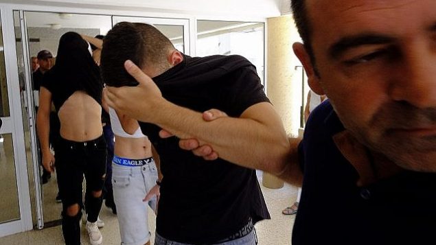 المشتبه بهم يغطون وجوههم خلال مغادرتهم لقاعة محكمة فاماغوستا حيث سيتم اقتيادهم إلى  مركز احتجاز في بارلماني، قبص، الخميس، 18 يوليو، 2019. محكمة قبرصية أمرت بتمديد اعتقال 12 سائحا إسرائيليا لثمانية أيام أخرى بعد أن زعمت سائحة بريطانية بأنهم قاموا باغتصابها.  (AP Photo/Petros Karadjias)