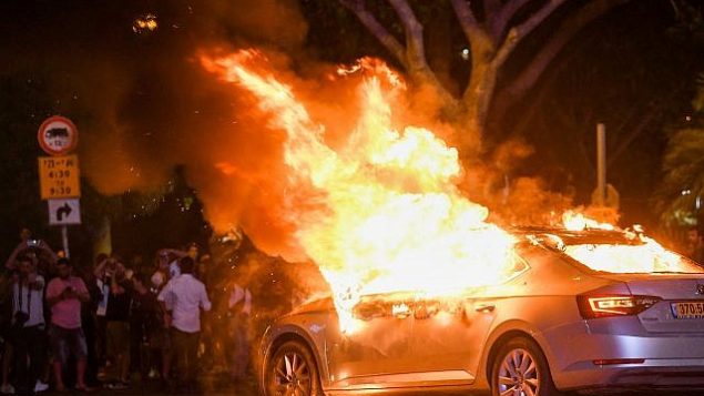 مركبة محترقة خلال احتجاجات في أعقاب مقتل الشاب من أصول إثيوبية سولومون تيكاه (19 عاما) قبل بضعة أيام في بلدة كريات يام برصاص شرطي خارج الخدمة، في مدينة تل أبيب، 2 يوليو، 2019. ( Flash90)