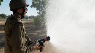 جندي اسرائيلي يستخدم خرطوم اطفاء (Israel Defense Forces)