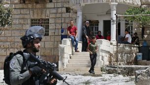 فلسطينيون يراقبون جنودا إسرائيليين خلال عملية بحث من بيت إلى بيت في قرية بيت فجار بالقرب من بيت لحم بالضفة الغربية، 8  أغسطس، 2019، في أعقاب هجوم طعن.  (HAZEM BADER / AFP)