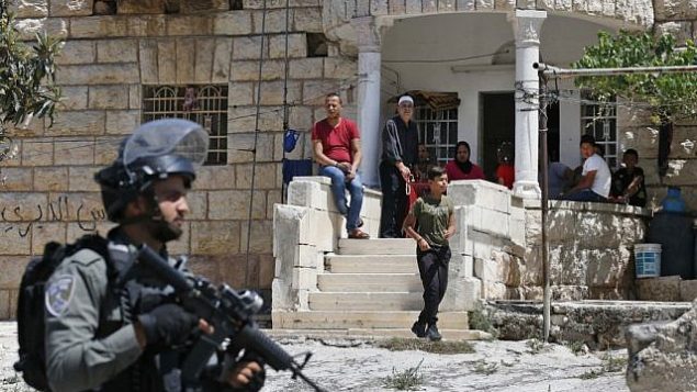 فلسطينيون يراقبون جنودا إسرائيليين خلال عملية بحث من بيت إلى بيت في قرية بيت فجار بالقرب من بيت لحم بالضفة الغربية، 8  أغسطس، 2019، في أعقاب هجوم طعن.  (HAZEM BADER / AFP)