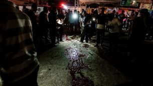 فلسطينيون يتفرجون على بقع دموية على الأرض بعد هجوم بالقرب من حاجز شرطة في مدينة غزة في 27 أغسطس، 2019. ( MAHMUD HAMS / AFP)