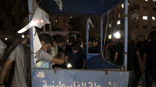 فلسطينيون يتفقدون الأضرار التي لحقت بكشك شرطة في أعقاب انفجار استهدف حاجزا للشرطة التابعة لحماس في مدينة غزة، الثلاثاء، 27 أغسطس، 2019. (AP Photo/Khalil Hamra)
