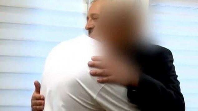 وزير الداخلية أرييه درعي يعانق رجلا فلسطينيا بعد أن سلمه الإقامة الإسرائيلية في 6 أغسطس، 2019. الرجل قدم المساعدة لعائلة مارك بعد تعرضها لهجوم وقع في 1 يوليو، 2016 راح ضحيته الحاخام ميكي مارك.  (Screencapture/Channel 12)