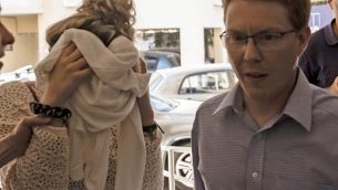 سائحة بريطانية (يسار)، المتهمة بتقديم بلاغ كذب بتعرضها للاغتصاب من قبل سياح إسرائيليين، تغطي وجهها عند وصولها إلى محاكمتها في محكمة مقاعطة فاماغوتسا في بارليمني بشرقي قبرص، 2 أكتوبر، 2019.  (Iakovos HATZISTAVROU/AFP)