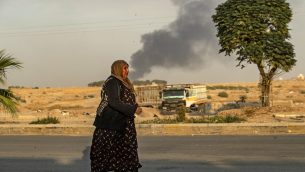 امرأة سورية تمشي امام دخان بينما يفر مدنيون عرب وأكراد بعد القصف التركي على بلدة رأس العين بشمال شرق سوريا في محافظة الحسكة على الحدود التركية، 9 اكتوبر 2019 (DELIL SOULEIMAN / AFP)