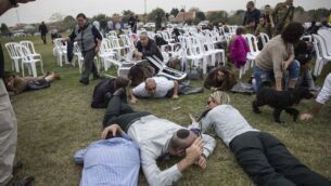 صورة توضيحية: إسرائيليون يحاولون الاختباء أثناء انطلاق صفارات إنذار في كيبوتس كفار عازة بالقرب من الحدود بين إسرائيل وغزة، 29 ديسمبر 2017. (AP / Tsafrir Abayov)