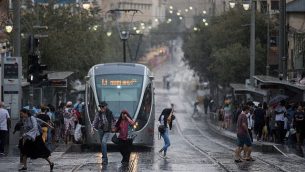 أشخاص يسيرون في أحوال جوية ماطرة وعاصفة في شارع يافا بالقدس، 15 أكتوبر، 2019. (Yonatan Sindel/Flash90)