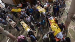 فلسطينيون يحملون جثامين رسمي أبو ملحوس وسبعة من أفراد عائلته، الذين قُتلوا في غارة جوية إسرائيلية استهدفت مزلهم، خلال جنازتهم في مسجد في بلدة دير البلح، وسط قطاع غزة، 14 نوفمبر، 2019.  (AP Photo/Khalil Hamra)