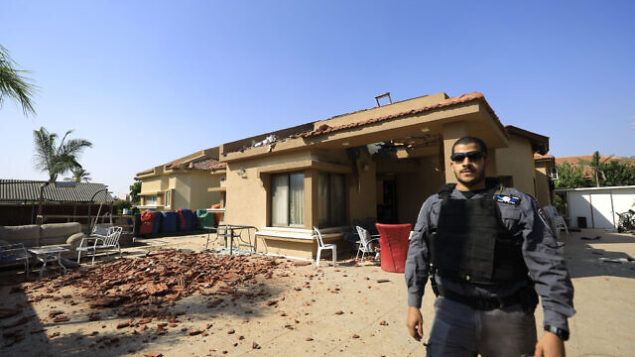 شرطي يقف أمام منزل أصيب بصاروخ أطلِق من قطاع غزة في مدينة نتيفوت، إسرائيل، 12 نوفمبر، 2019. (Tsafrir Abayov/AP)