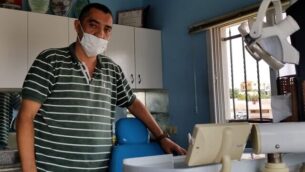 أمين منصور (47 عاما)، طبيب أسنان من قرية عزون الفلسطينية بالضفة الغربية يقف في عيادته، 20 أكتوبر، 2019. (Adam Rasgon/ Times of Israel)