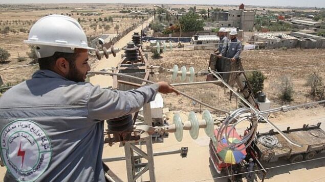توضيحية: عمال كهرباء فلسطينيين يتفقدون منشآت كهرباء في مدينة رفج بجنوب غزة،  25 يونيو، 2019.(Said Khatib/AFP)
