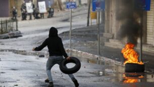 متظاهر فلسطيني يرمي إطارًا أثناء أثناء اشتباكات مع قوات الأمن الإسرائيلية في مدينة الخليل جنوب الضفة الغربية، 9 ديسمبر 2019، وسط إضراب عام احتجاجا على النشاط الاستيطاني الإسرائيلي. (HAZEM BADER / AFP)