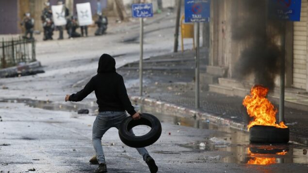 متظاهر فلسطيني يرمي إطارًا أثناء أثناء اشتباكات مع قوات الأمن الإسرائيلية في مدينة الخليل جنوب الضفة الغربية، 9 ديسمبر 2019، وسط إضراب عام احتجاجا على النشاط الاستيطاني الإسرائيلي. (HAZEM BADER / AFP)