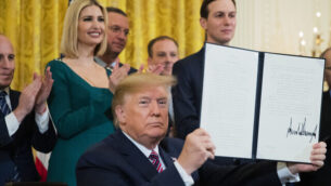 President Donald Trump shows the executive order he signed combatting anti-Semitism in the U. S. during a Hanukkah reception in the East Room of the White House Wednesday, Dec. 11, 2019, in Washington. (AP Photo/Manuel Balce Ceneta)
