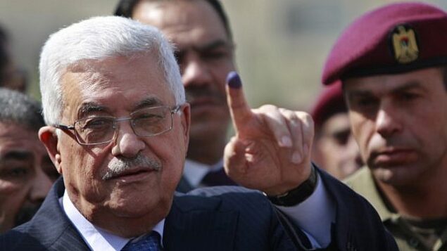 رئيس السلطة الفلسطينية محمود عباس يرفع أصبعه الملون بالحبر بعد الإدلاء بصوته خلال الانتخابات المحلية في مركز اقتراع بمدينة رام الله بالضفة الغربية، 20 أكتوبر، 2012. (AP/Majdi Mohammed)