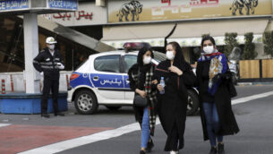 صورة توضيحية: أحد رجال الشرطة والمشاة يرتدون أقنعة للحماية من فيروس كورونا، في وسط طهران، إيران، 23 فبراير 2020. (Ebrahim Noroozi / AP)