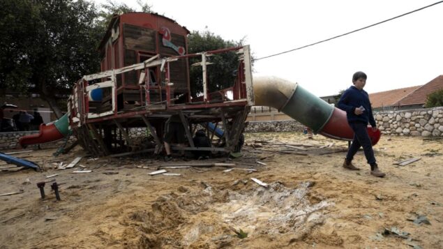 طفل يسير داخل ملعب روضة أطفال أصيب بصاروخ أطلق من قطاع غزة في مدينة سديروت، 24 فبراير 2020. (AP Photo / Tsafrir Abayov)