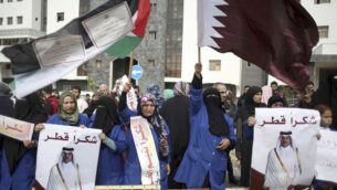 عمال النظافة في المستشفيات يحملون لافتات شكر لقطر ويلوحون بالأعلام القطرية والفلسطينية خلال مؤتمر صحفي لماتياس شمالي، مدير الأونروا في غزة، والمبعوث القطري محمد العمادي، في مستشفى الشفاء في مدينة غزة، 19 فبراير 2018. (AP Photo/Khalil Hamra)