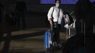 سيدة تضع قناعا واقيا عند وصولها إلى مطار بن غوريون، بالقرب من تل أبيب، 27 فبراير، 2020.  (AP/Ariel Schalit)