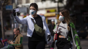 امرأتان تلتقطان صورة سلفي مع أقنعة الوجه في تل أبيب، 15 مارس 2020 (AP / Oded Balilty)