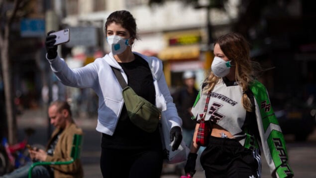 امرأتان تلتقطان صورة سلفي مع أقنعة الوجه في تل أبيب، 15 مارس 2020 (AP / Oded Balilty)