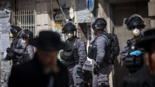 عناصر شرطة إسرائيلية في حي ’مئة شعاريم’ الحريدي بالقدس يقومون بإغلاق المحلات التجارية وتفريق التجمعات العامة عقب قرارات الحكومة التي صدرت في محاولة لاحتواء انتشار فيروس كورونا، 24 مارس، 2020. (Yonatan Sindel/Flash90)