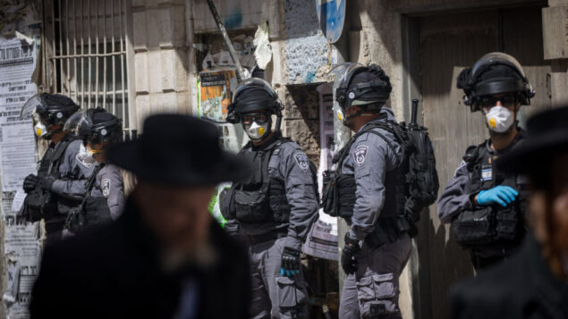 عناصر شرطة إسرائيلية في حي ’مئة شعاريم’ الحريدي بالقدس يقومون بإغلاق المحلات التجارية وتفريق التجمعات العامة عقب قرارات الحكومة التي صدرت في محاولة لاحتواء انتشار فيروس كورونا، 24 مارس، 2020. (Yonatan Sindel/Flash90)
