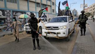عناصر في الجناح العسكري لحركة الجهاد الإسلامي الفلسطينينة، سرايا القدس، يقومون بإجراءات تعقيم في شوارع مدينة رفح جنوبي قطاع غزة، 26 مارس، 2020. (Said Khatib/AFP)