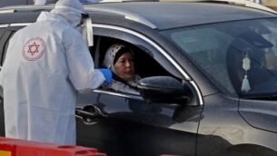 مسعف نجمة داود الحمراء يختبر امرأة لفيروس كورونا في موقع اختبار ’درايف ثرو’ في مدينة طمرة الشمالية، 31 مارس 2020 (Ahmad Gharabli / AFP)