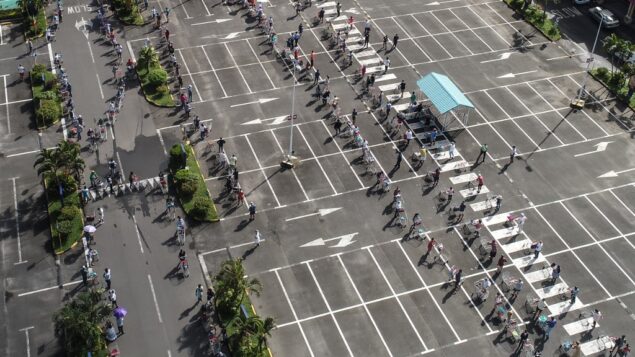 صورة جوية تظهر أشخاص ينتظرون أثناء الحفاظ على التباعد الاجتماعي في موقف للسيارات قبل دخول سوبر ماركت في موريشيوس، 2 أبريل 2020 (L'EXPRESS MAURICE / AFP)